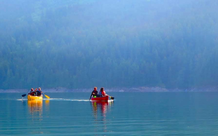 two canoes are paddled by outward bound students on calm blue water